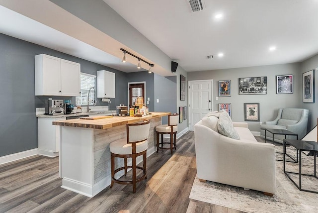 kitchen featuring white cabinets, wood counters, a breakfast bar, hardwood / wood-style floors, and a kitchen island