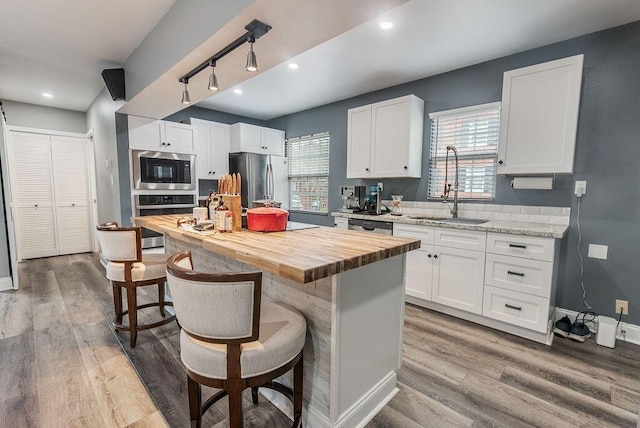 kitchen with appliances with stainless steel finishes, white cabinets, a breakfast bar, a kitchen island, and sink