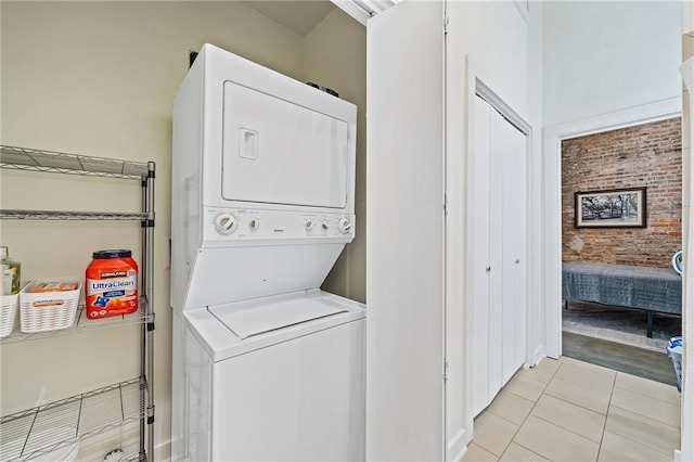 204 Conti St Unit 1A, Mobile, AL 36602 - laundry room with estacked washer and dryer, brick wall, and light tile patterned floors
