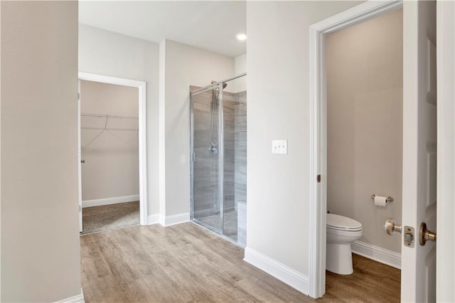 bathroom with hardwood / wood-style flooring, toilet, and a shower with door