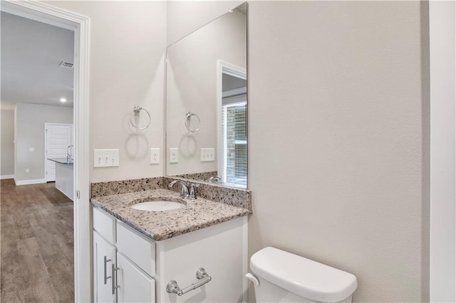 bathroom with hardwood / wood-style flooring, vanity, and toilet