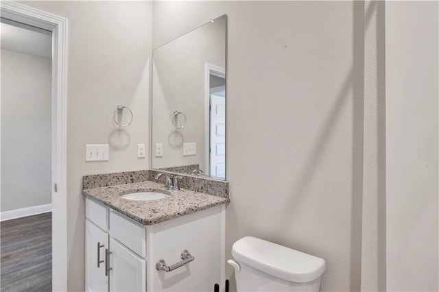 bathroom with hardwood / wood-style floors, vanity, and toilet