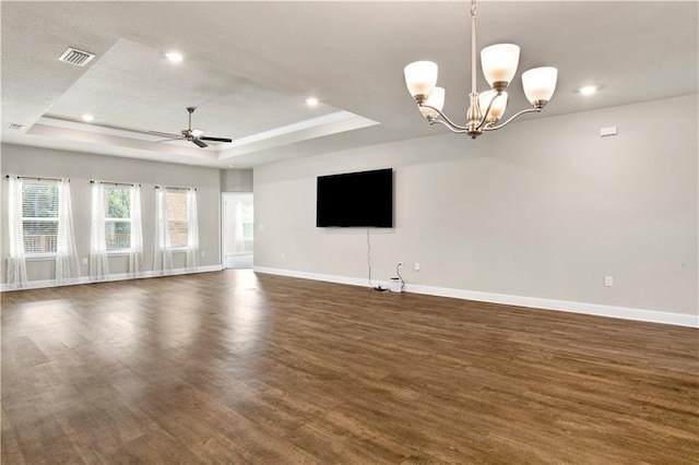 unfurnished living room featuring a tray ceiling, dark hardwood / wood-style flooring, and ceiling fan with notable chandelier