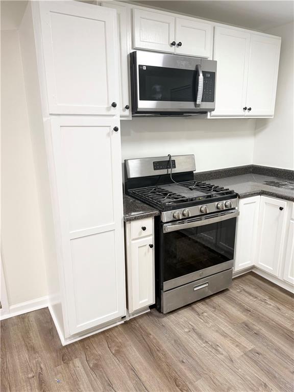 kitchen featuring stainless steel appliances, white cabinetry, and light wood finished floors