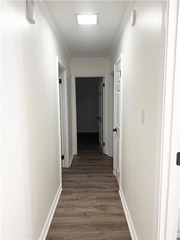 corridor with dark wood-style flooring, baseboards, and ornamental molding