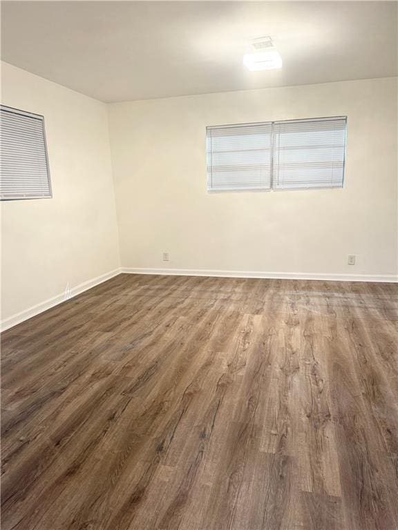 spare room featuring baseboards and dark wood-style floors