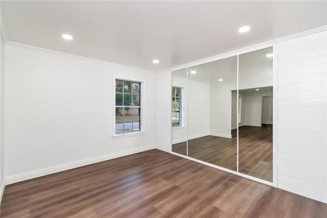 unfurnished bedroom with a closet, crown molding, and dark hardwood / wood-style flooring