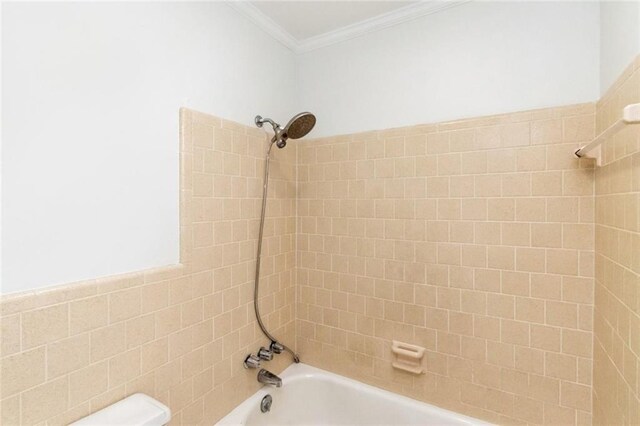 bathroom featuring toilet, crown molding, and tiled shower / bath combo