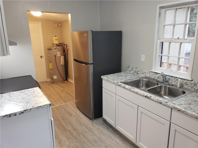 kitchen featuring stainless steel fridge, water heater, plenty of natural light, and white cabinets