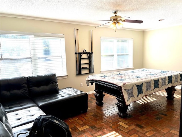 recreation room with a textured ceiling, ceiling fan, and ornamental molding