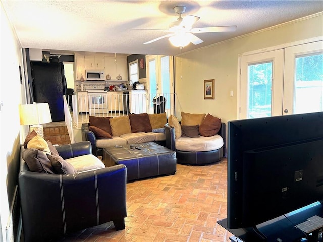 living room featuring french doors, a textured ceiling, crown molding, and ceiling fan