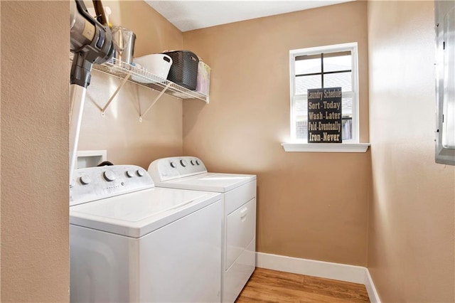 clothes washing area featuring laundry area, separate washer and dryer, light wood-style flooring, and baseboards