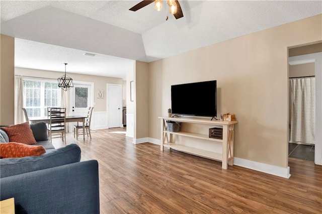 living room featuring lofted ceiling, a textured ceiling, wood finished floors, a ceiling fan, and baseboards