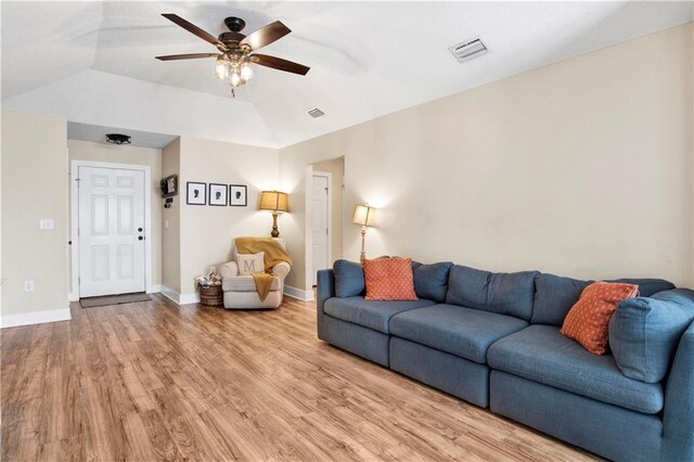 living room featuring a ceiling fan, light wood-type flooring, visible vents, and baseboards