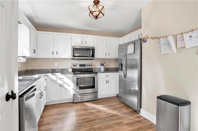 kitchen featuring stainless steel appliances, light wood finished floors, and white cabinets