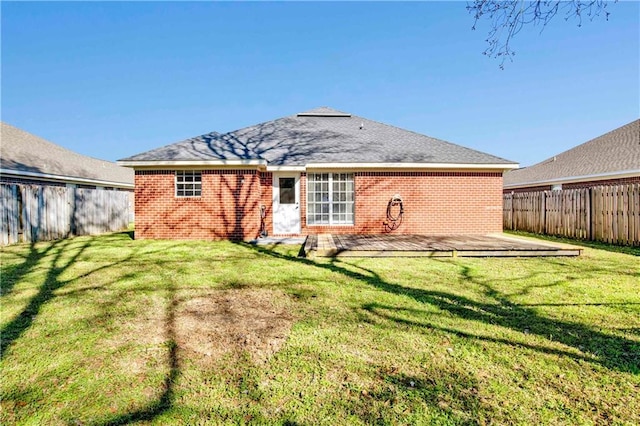 back of house featuring a deck, a yard, brick siding, and a fenced backyard