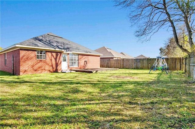 back of house featuring a patio, a playground, a fenced backyard, brick siding, and a lawn