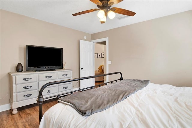 bedroom featuring wood finished floors, a ceiling fan, and baseboards