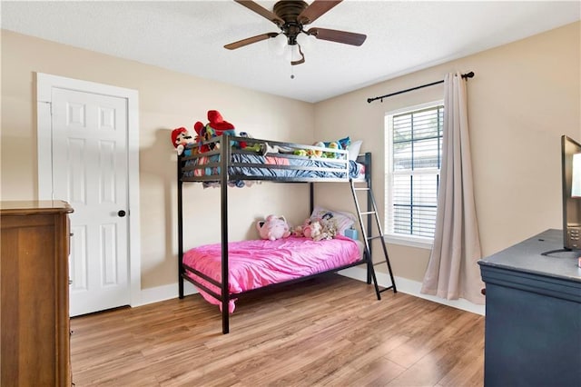 bedroom featuring wood finished floors, a ceiling fan, and baseboards