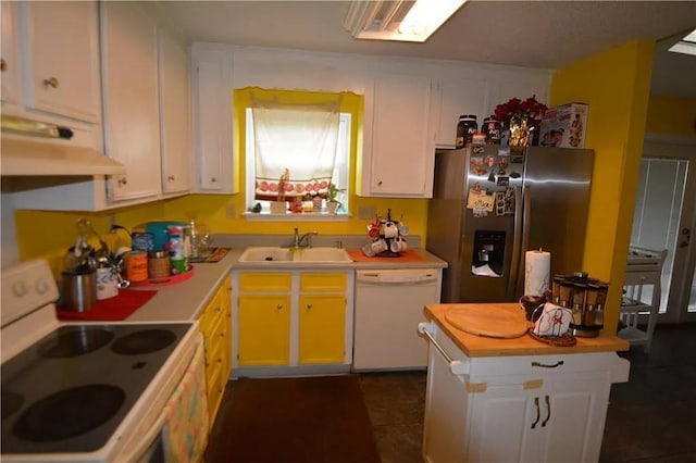 kitchen featuring dark tile patterned flooring, white cabinets, white appliances, and sink