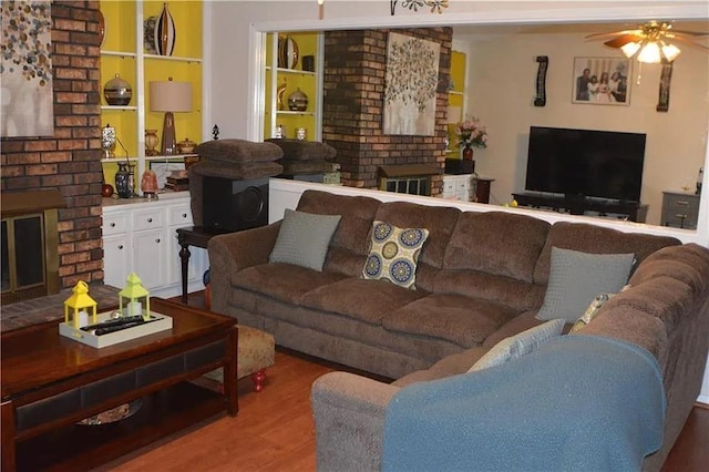 living room featuring ceiling fan, a brick fireplace, and light hardwood / wood-style floors