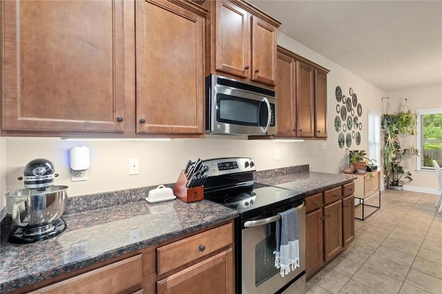 6120 Whitebark Dr, Mobile, AL 36693 - kitchen with stainless steel appliances, light tile patterned floors, dark stone counters, and brown cabinetry