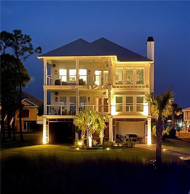 back of house at twilight with a balcony