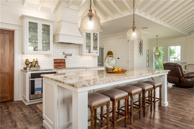 kitchen with tasteful backsplash, open floor plan, dark wood-style floors, custom exhaust hood, and white cabinetry