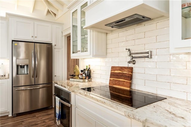 kitchen featuring ventilation hood, white cabinets, tasteful backsplash, and appliances with stainless steel finishes