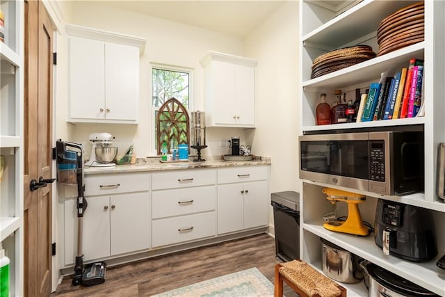 kitchen featuring stainless steel microwave, white cabinets, dark wood-type flooring, and open shelves