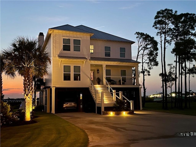 raised beach house featuring stairway, concrete driveway, metal roof, a carport, and a standing seam roof