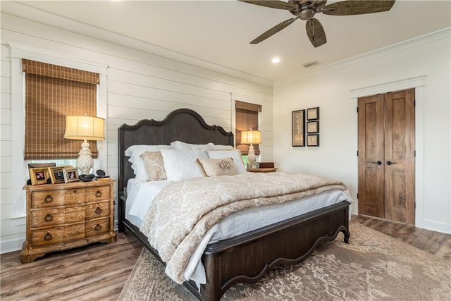 bedroom with a ceiling fan, wood finished floors, visible vents, recessed lighting, and ornamental molding