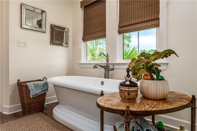 bathroom featuring wood finished floors, baseboards, and a freestanding bath