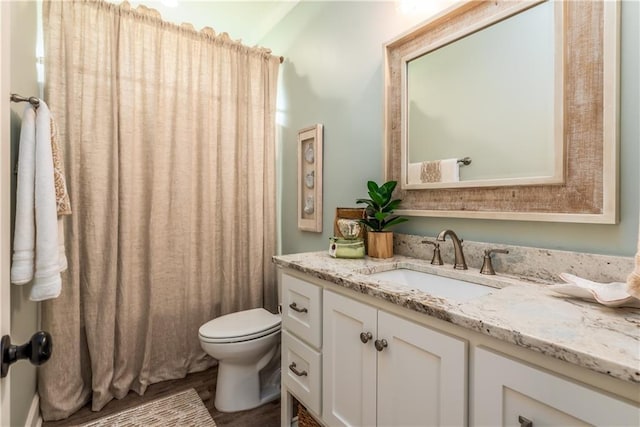 full bath with toilet, vanity, and wood finished floors