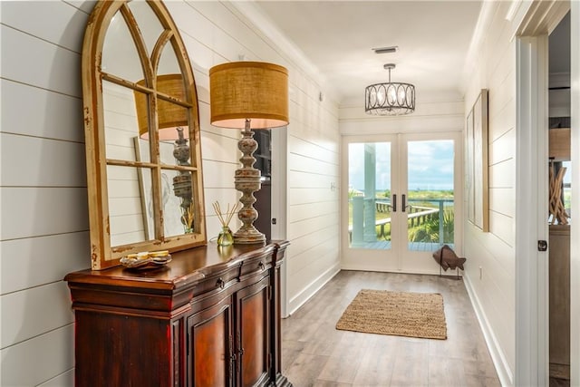 doorway to outside featuring visible vents, a notable chandelier, wood finished floors, french doors, and crown molding