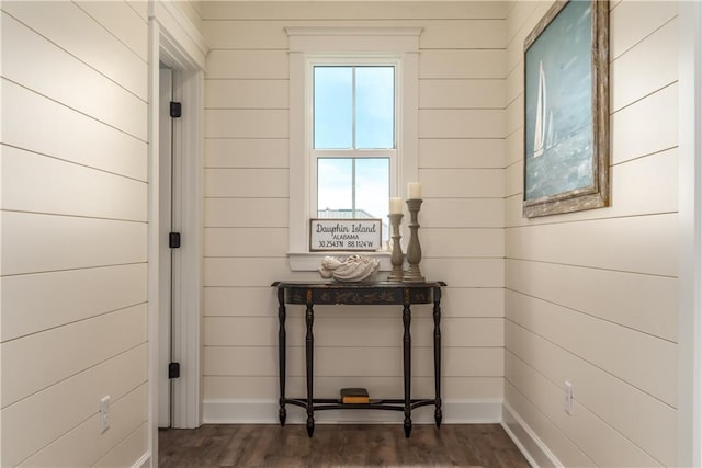 corridor with baseboards, dark wood-type flooring, and wood walls