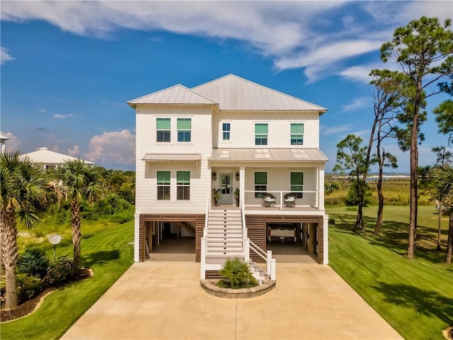 coastal inspired home featuring a carport, stairway, a porch, and a front lawn