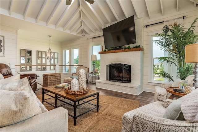 living area with a wealth of natural light, vaulted ceiling with beams, wood finished floors, and a fireplace