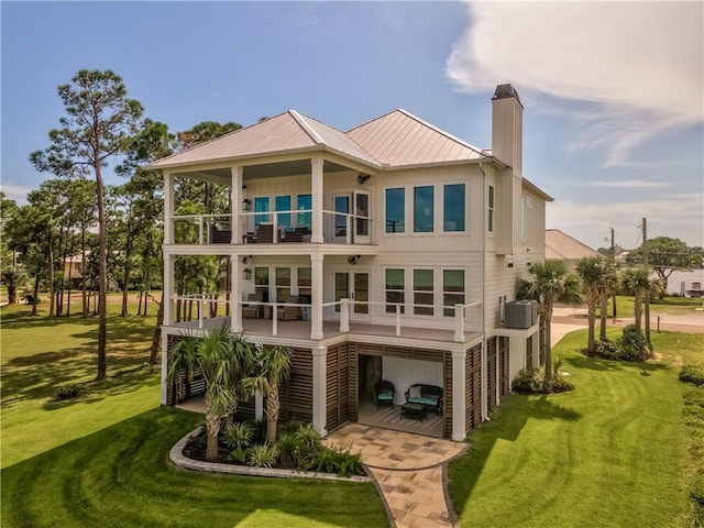 back of property featuring stairway, a balcony, central air condition unit, a lawn, and metal roof