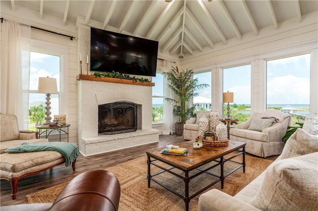 living room featuring a fireplace, lofted ceiling with beams, and wood finished floors