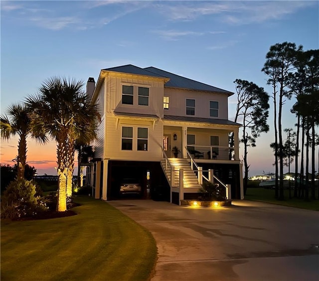 raised beach house featuring a carport, stairway, covered porch, and driveway