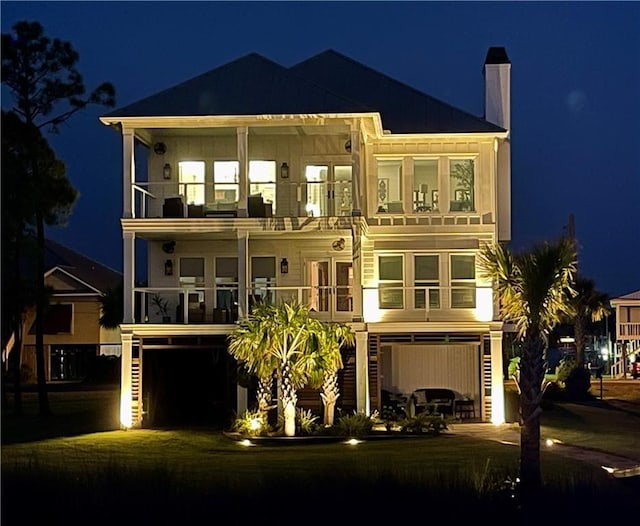 back of house at twilight with board and batten siding and a balcony