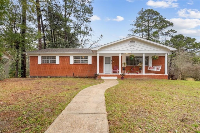 view of front facade featuring a porch, a front yard, and brick siding