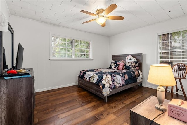 bedroom with dark wood finished floors, a ceiling fan, and baseboards