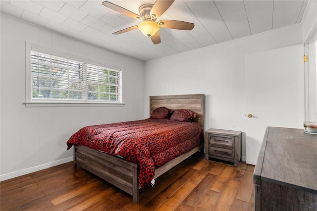 bedroom with ceiling fan, dark wood-type flooring, and baseboards