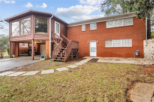 view of front of house with driveway, a front yard, stairway, and brick siding