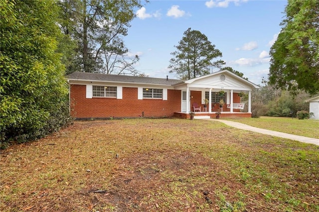 view of front facade featuring covered porch, brick siding, and a front yard