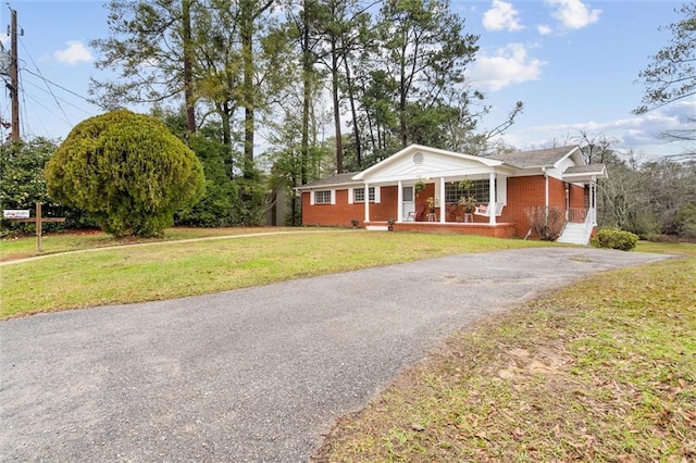 view of front of home featuring a porch, a front lawn, aphalt driveway, and brick siding