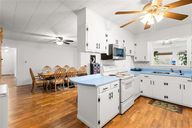 kitchen featuring white electric stove, white cabinets, stainless steel microwave, light countertops, and a sink