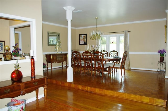 dining room featuring crown molding, parquet flooring, a chandelier, and ornate columns